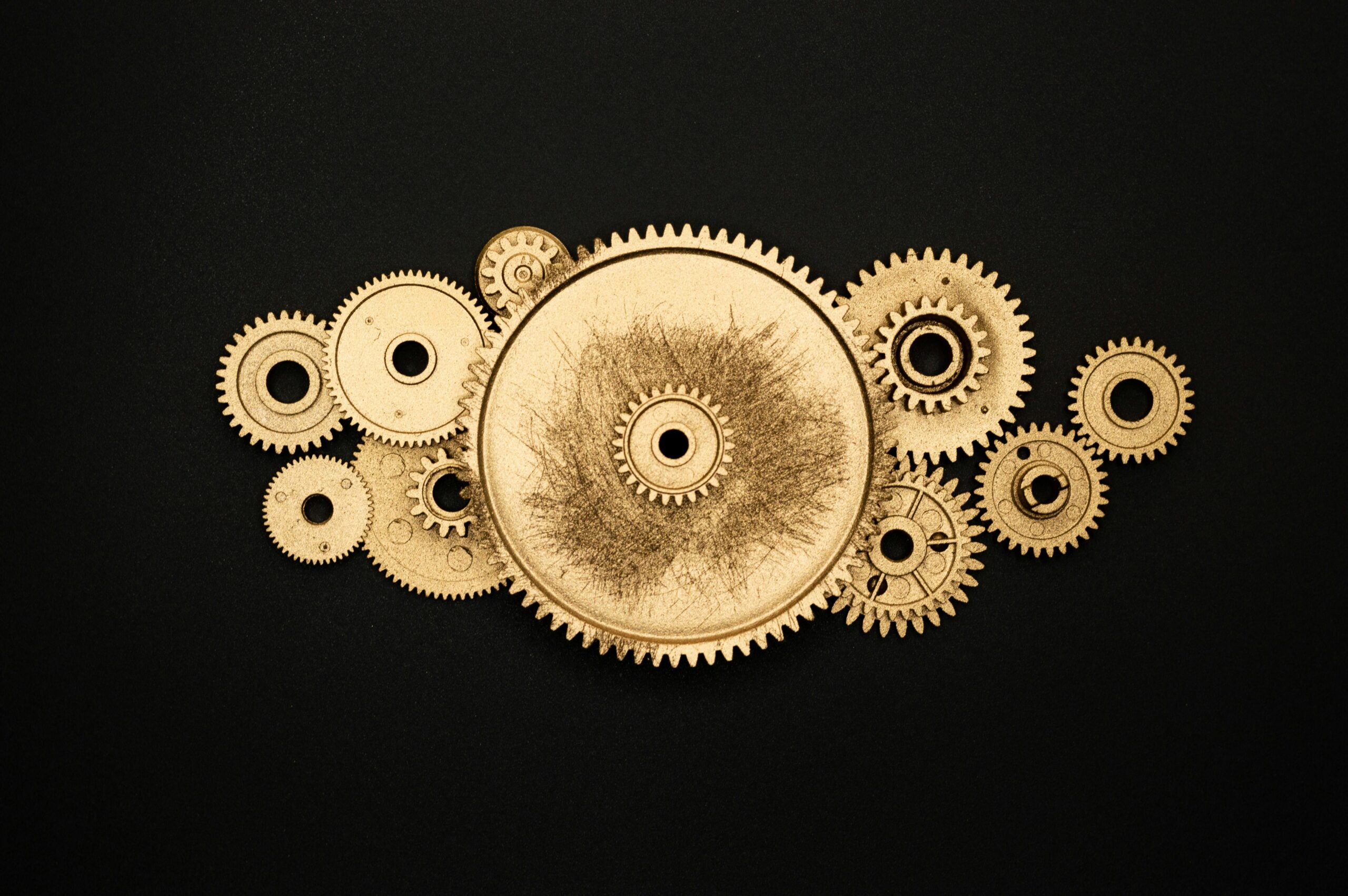 Artistic arrangement of gold gears on a black background symbolizing industry.